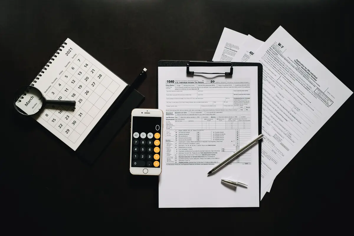 Tax forms, a calculator and a calendar laid out on a desk
